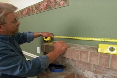 measuring for a decorative wall frame above the fireplace