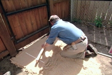 leveling sand with screed rails and a two-by-four