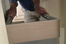positioning the pull-out waste bin base against the cabinet