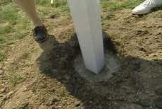 forcing the vinyl picket fence posts into the cement