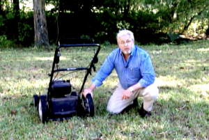 Man with lawnmower on dry grass during drought conditions
