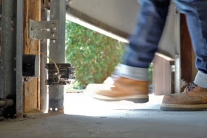 Foot with construction boot under garage door