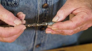 Man demonstrates how to screw a bolt into wood