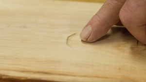 Man pointing to dent in unfinished wood