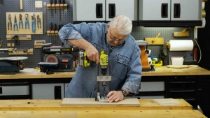  Man uses a portable drill press to drill a straight hole