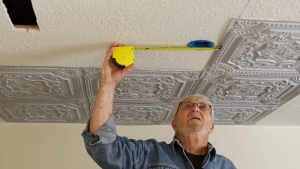 Man using tape measure on ceiling