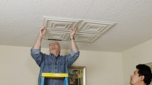 Man pressing foam tile on ceiling