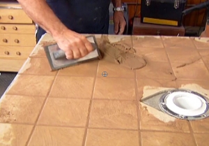 hand spreading grout on tile with trowel 
