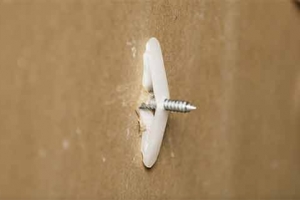 The backside of a wall board with a toggle wall anchor