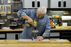  Man uses a portable drill press to drill a straight hole