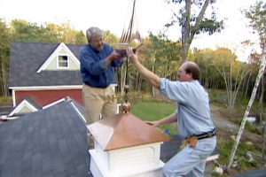 men installing weathervane and cupola on roof