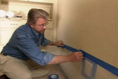 taping plastic sheeting onto wall