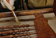 applying wood stain to the antique chair