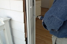 Removing a screw that is holding the old patio door unit into the opening
