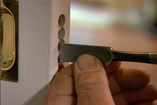 Using a chisel to remove excess wood in the latch opening
