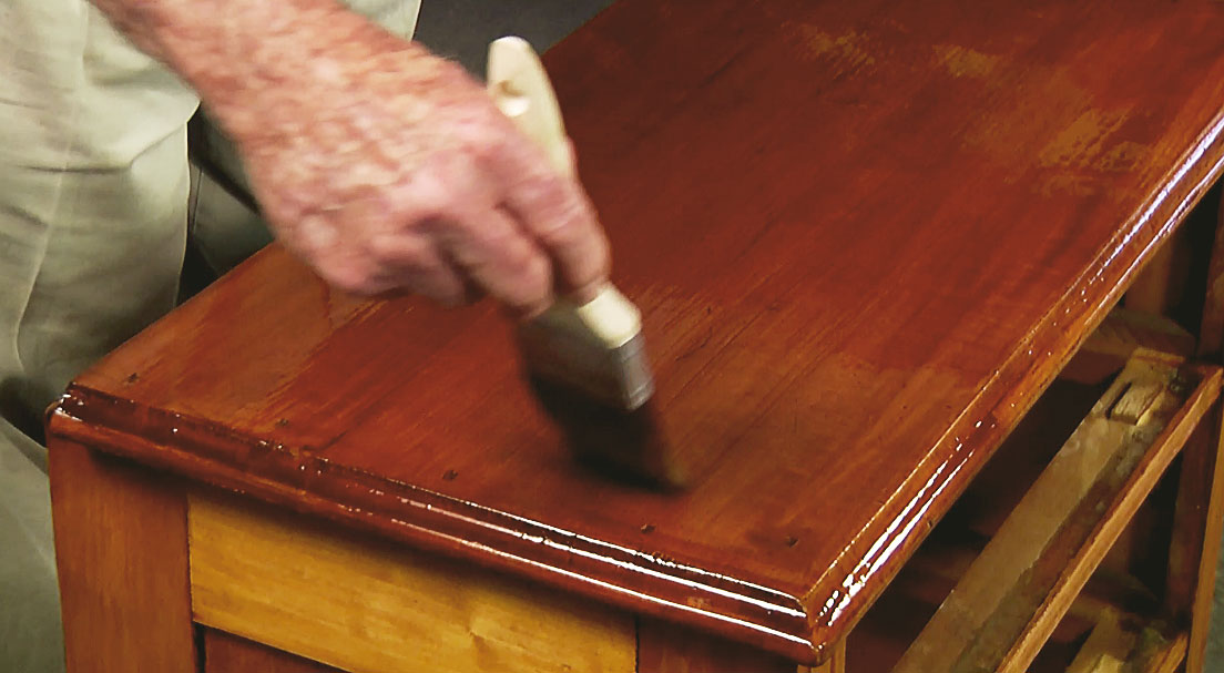 Man brushing top of wooden chest 