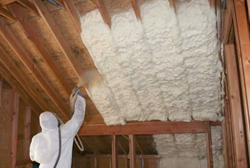Man spraying foam insulation in attic