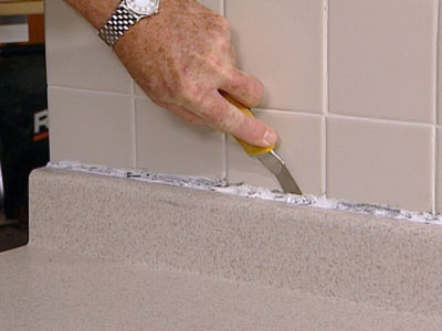 Cutting old sealant in bathroom backsplash 