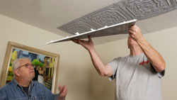 Two men installing decorative celing PVC tile 