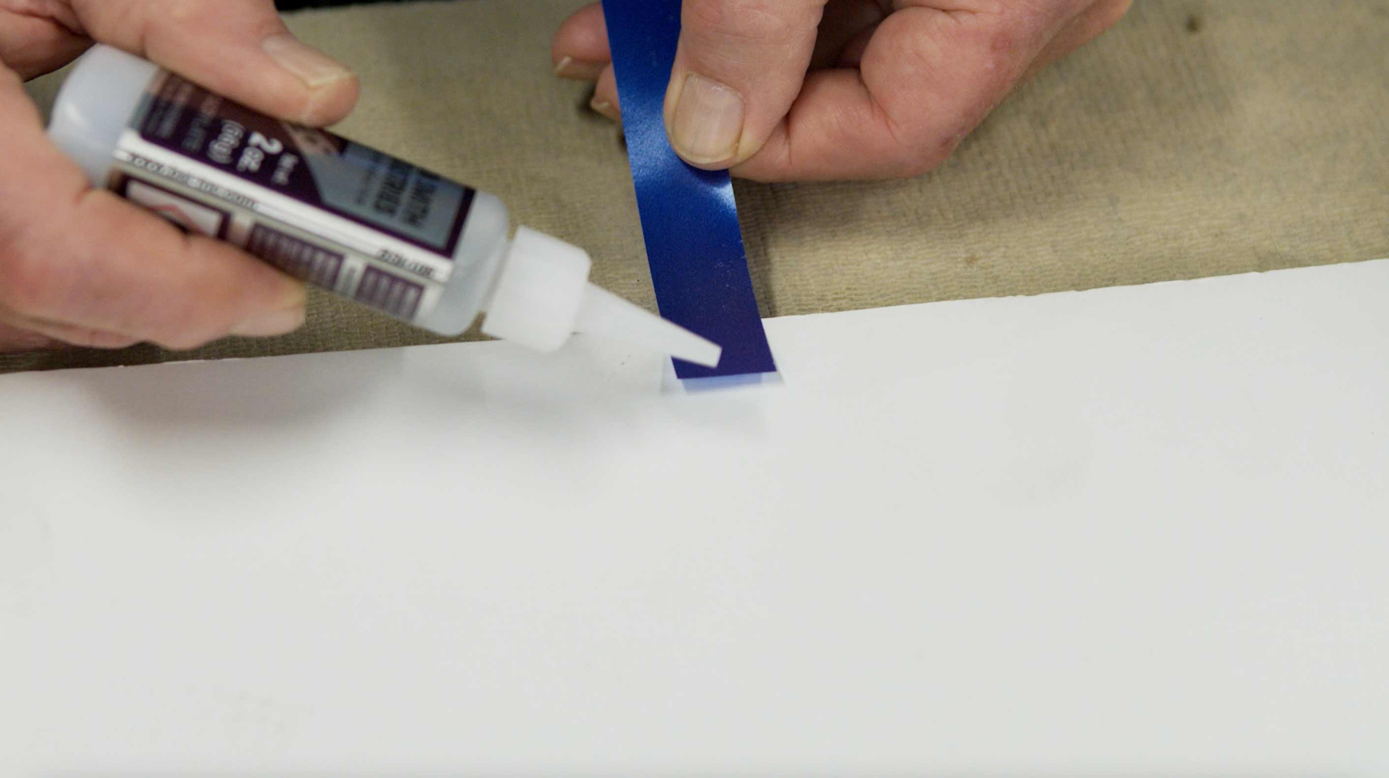 Man applying glue to ribbon to make a pull tab