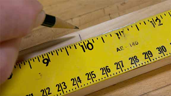 Man marking a measure on a piece of wood