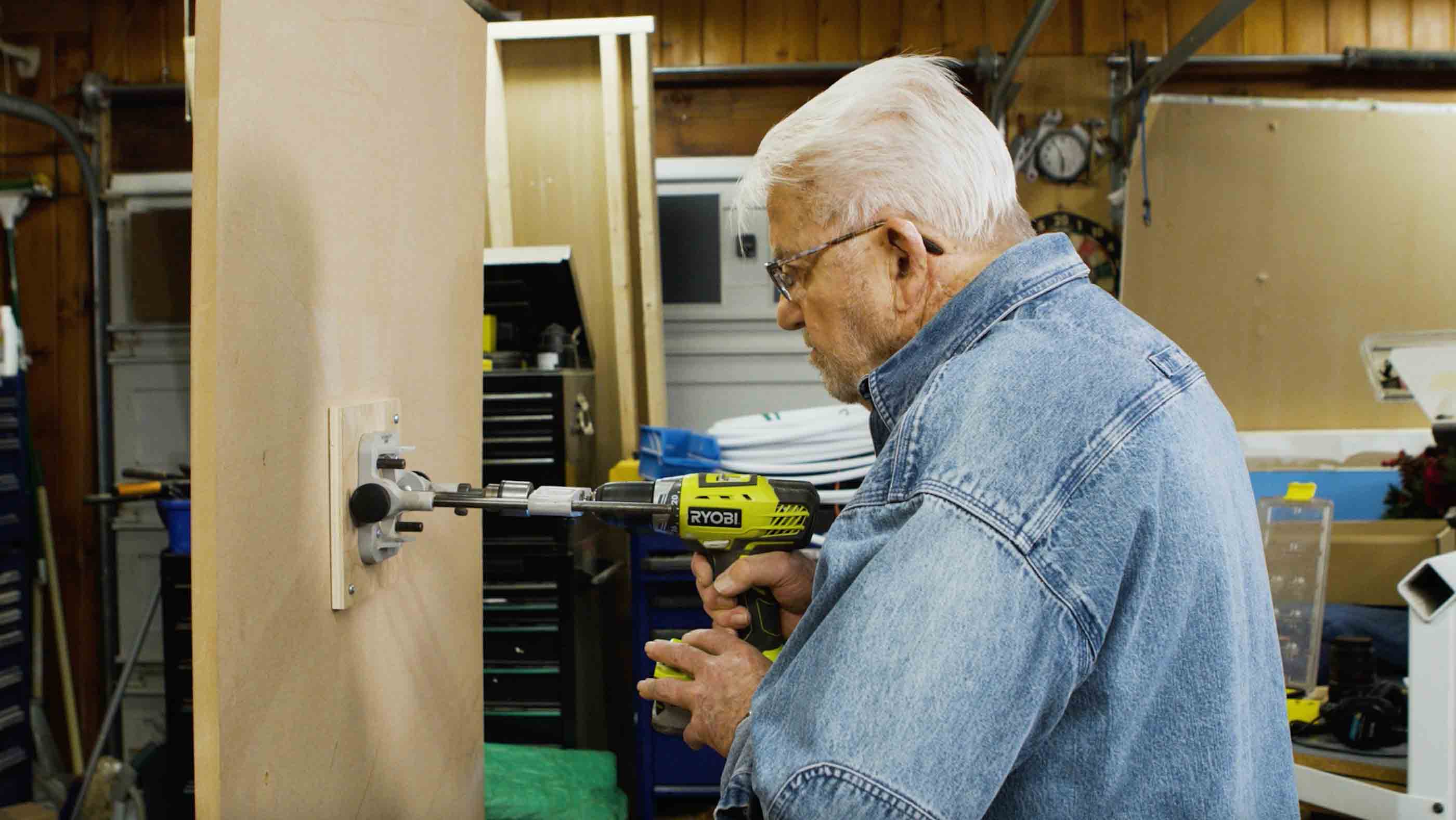 Man uses portable drill press to drill into a vertical surface