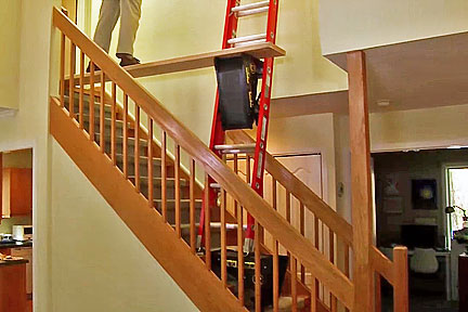 A pivot ladder sits on stairs to help you reach tall spaces