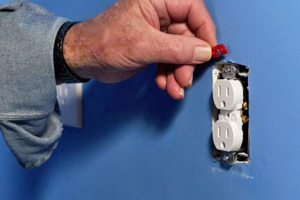 Man uses a spacer to fix a loose electrical socket