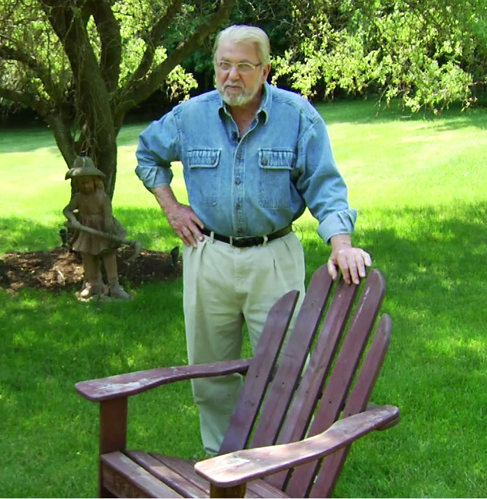 Man standing with wooden adirondack chair