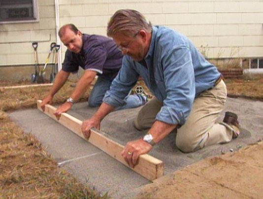 Two men preparing sand for patio