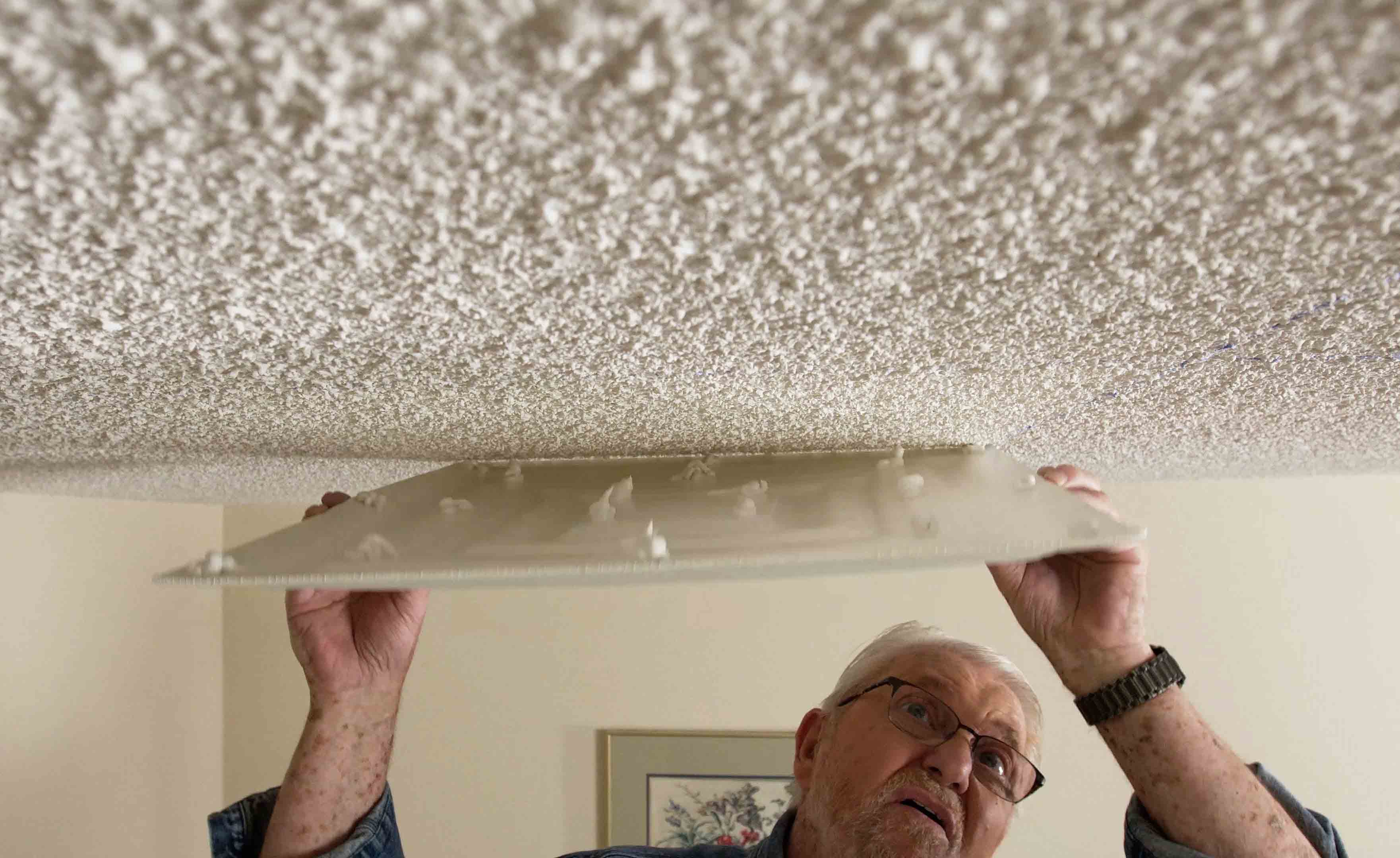 Man setting ceiling tile in place